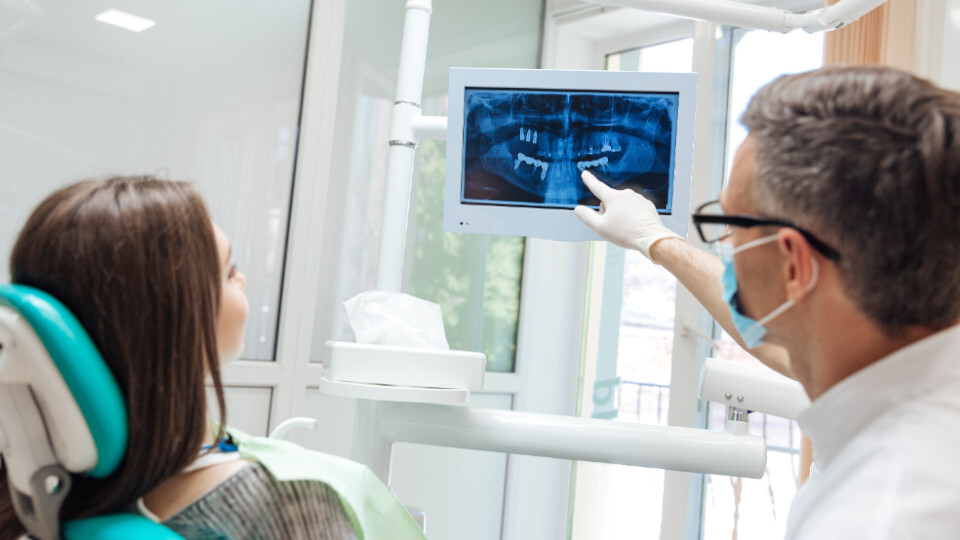 Ein Zahnarzt erklärt einer Patientin eine Röntgenaufnahme
